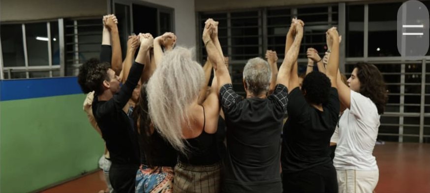 Elenco de mãos dadas em roda no ensaio