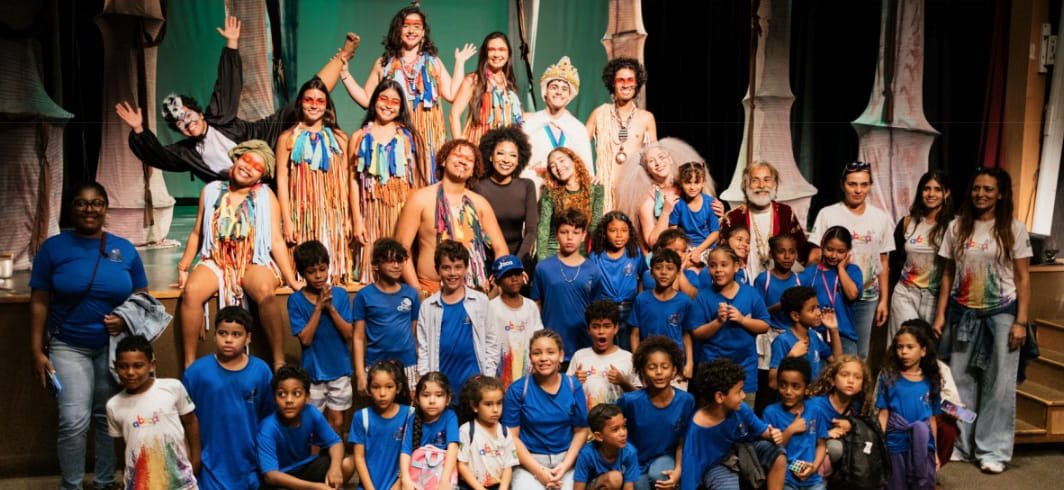 Crianças de camisa azul com o elenco no palco