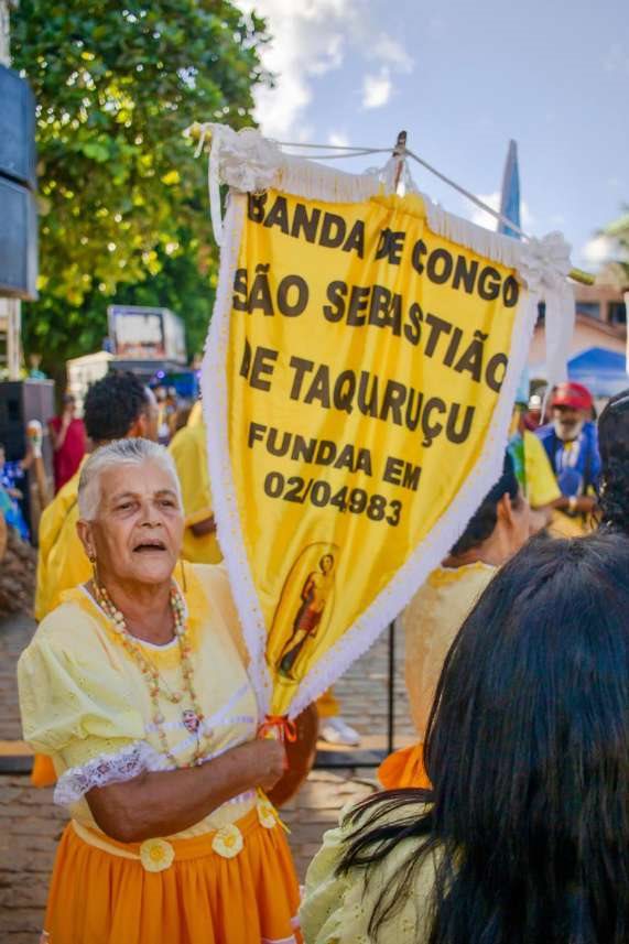 Senhora carrega a bandeira da banda de congo São Sebastião